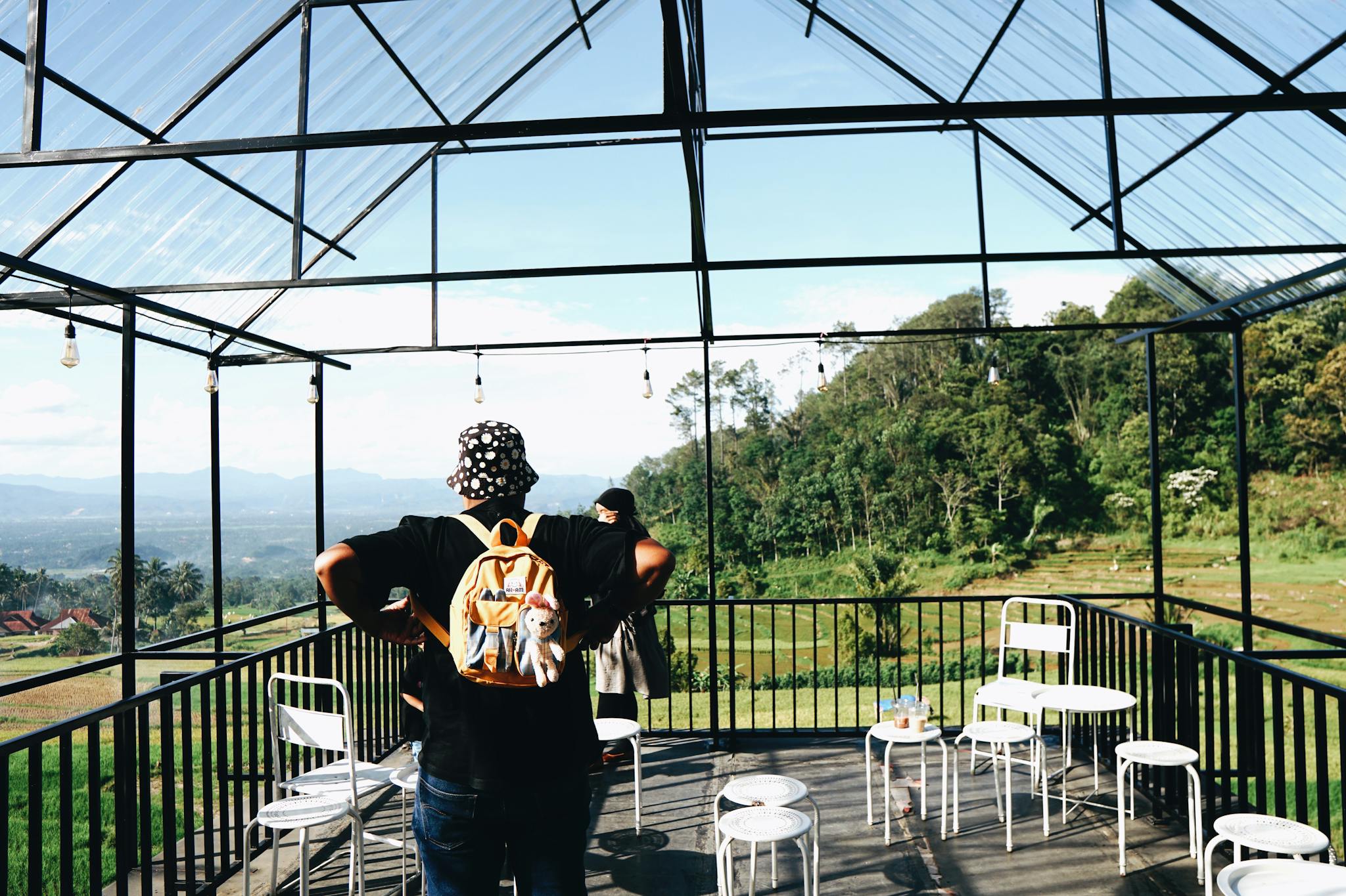 People enjoying a scenic mountain view from a modern café terrace in Sumatera Barat, Indonesia.